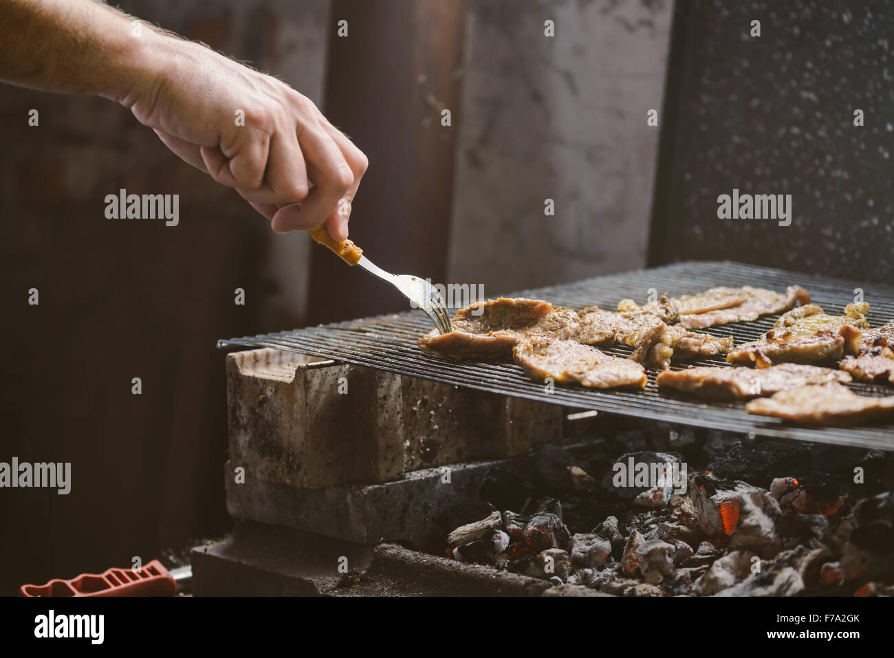 L uomo per grigliare carne di maiale braciole sul barbecue, dai toni retrò, messa a fuoco selettiva con profondità di campo ridotta. Foto Stock