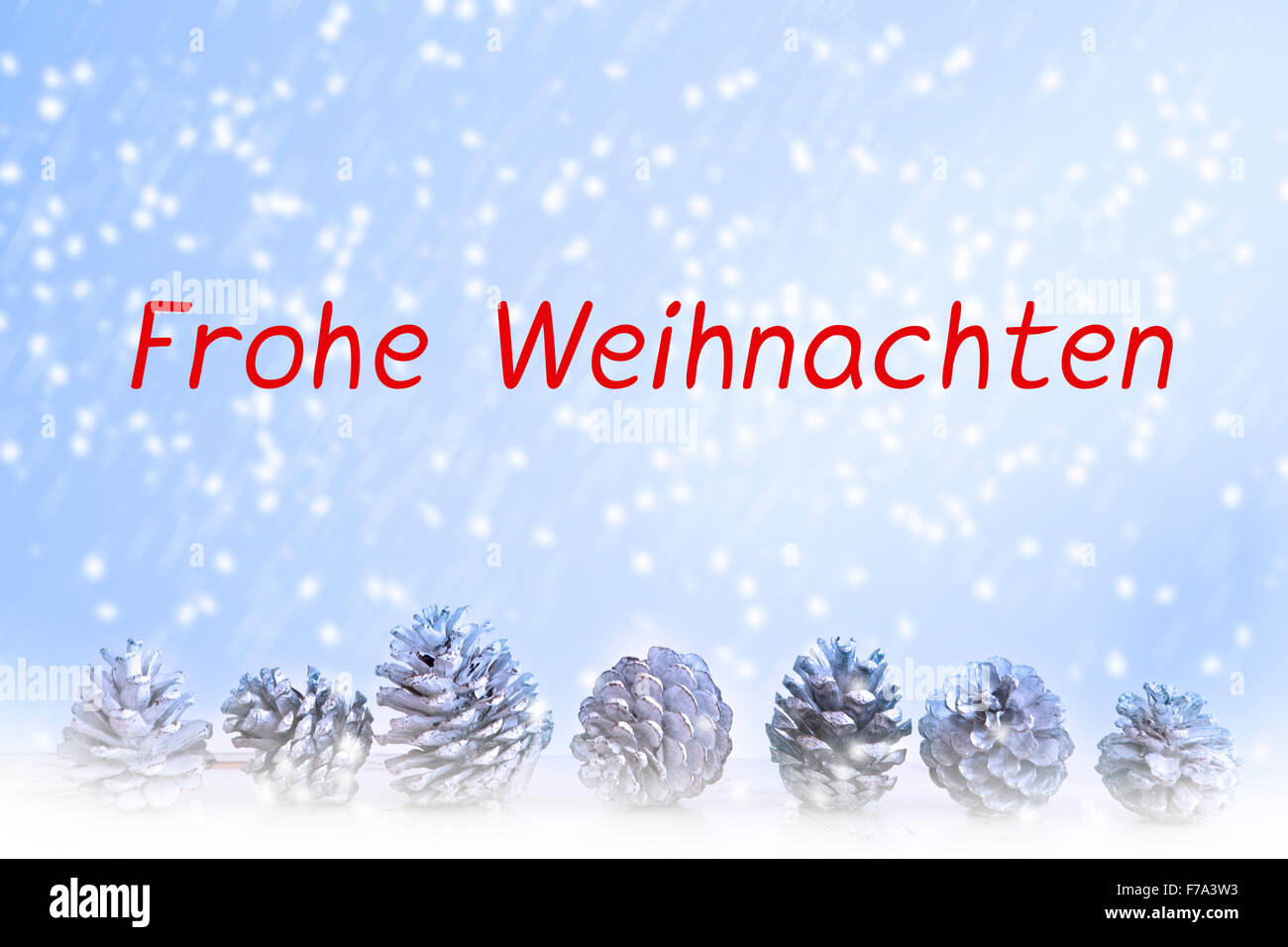 I tedeschi 'Frohe Weihnachten' scritta su sfondo blu con i fiocchi di neve e pigne nelle quali Foto Stock