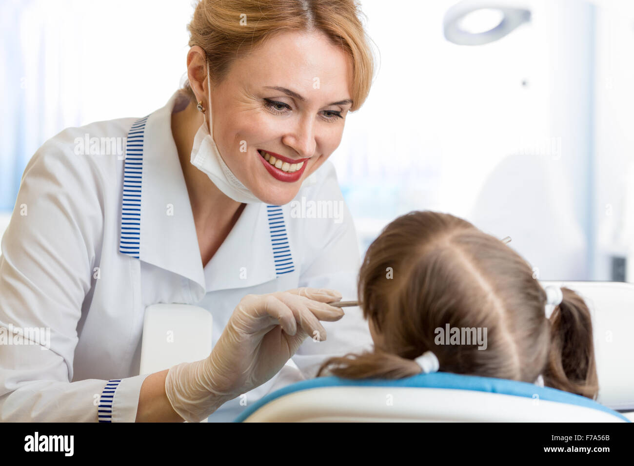 Sorridente dentista donna esame paziente di capretto in clinica Foto Stock