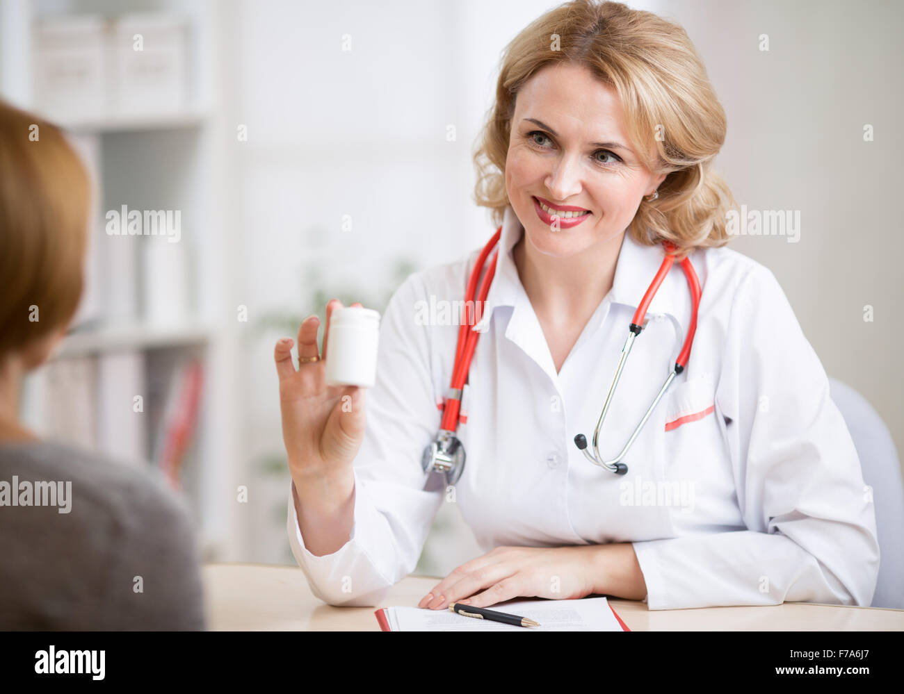 Medico donna che mostra la medicina può al paziente nel suo ufficio Foto Stock