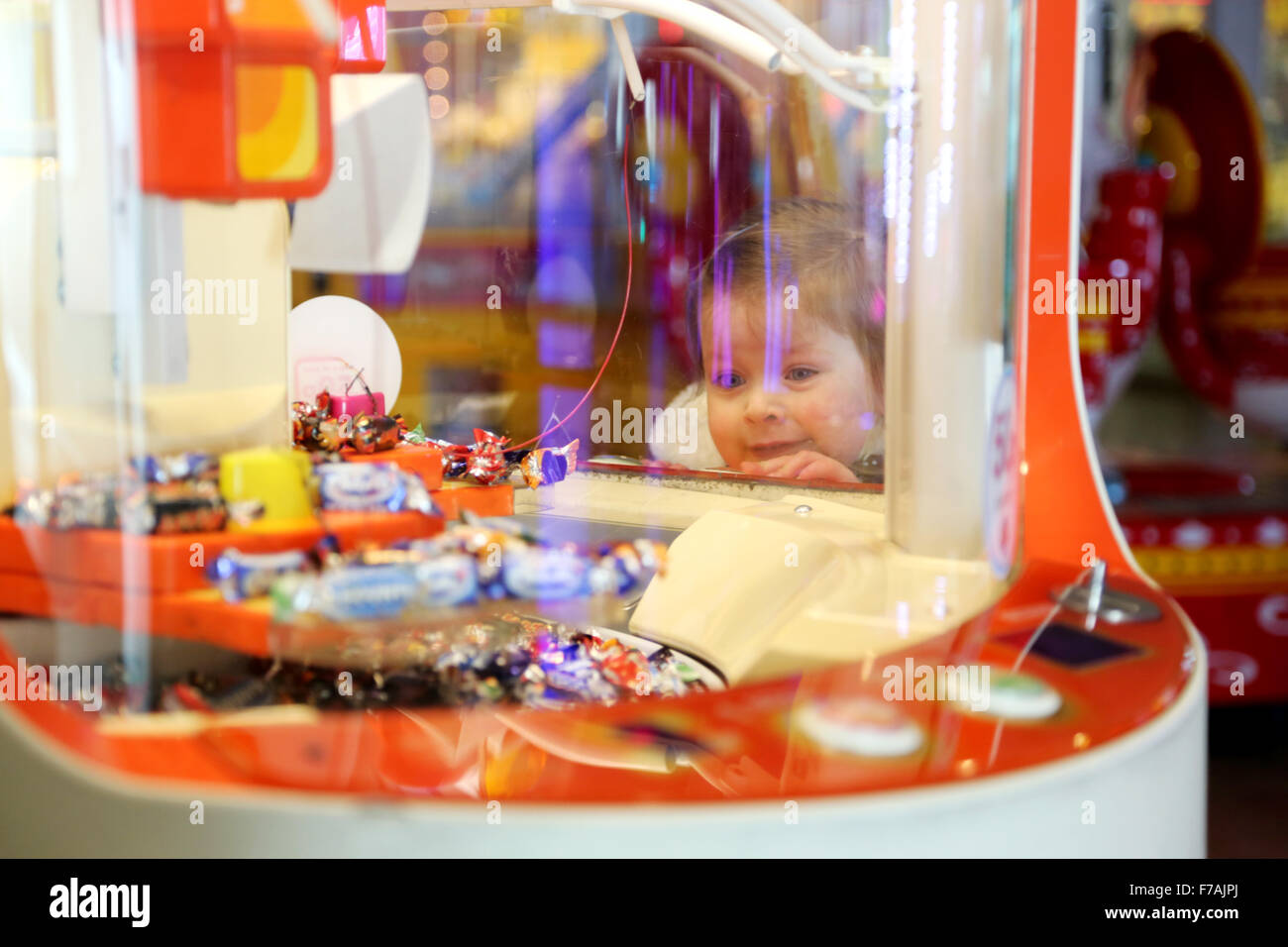 Un giovane bambino cercando in un grab macchina in un tradizionale inglese divertimento arcade. La macchina offre dolci e caramelle come premi Foto Stock