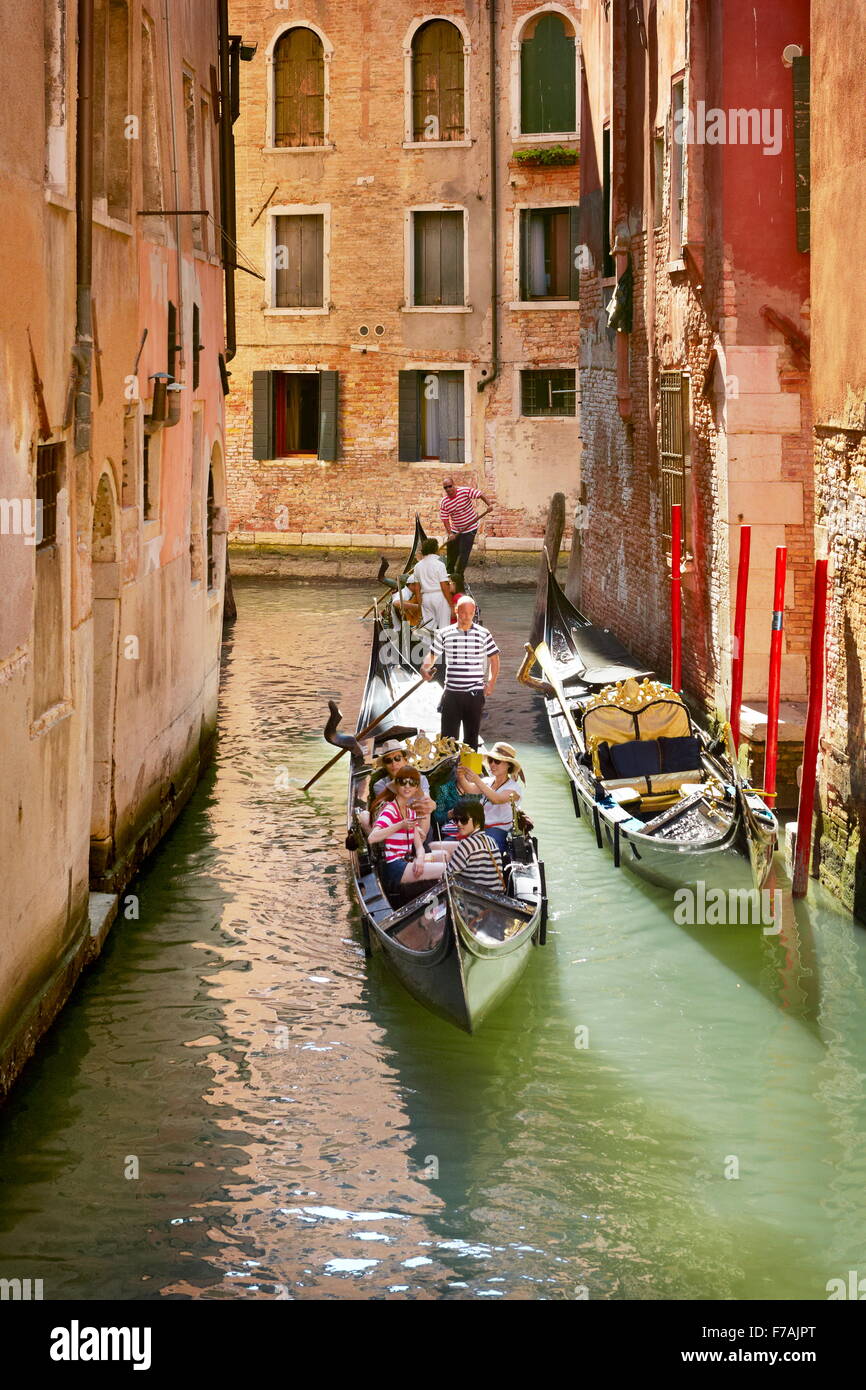 Turisti in gondola esplorare canale veneziano, Venezia, Veneto, Italia Foto Stock