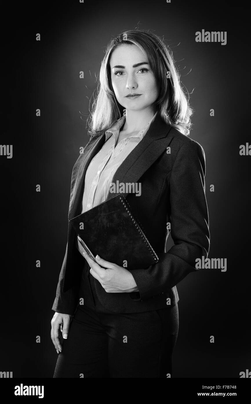 Ritratto di una donna d'affari shot in studio su sfondo grigio in possesso di un notebook e penna Foto Stock