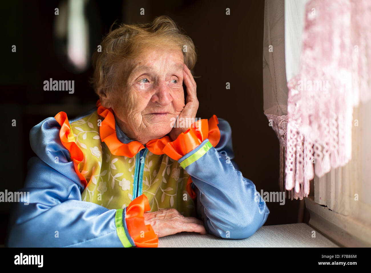 Donna anziana tristemente guardando fuori dalla finestra. Foto Stock