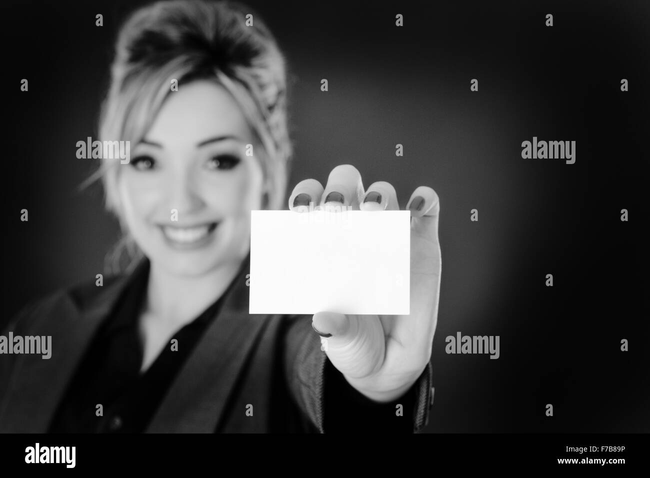 Business donna con in mano una businesscard shot in studio su sfondo grigio. Foto Stock