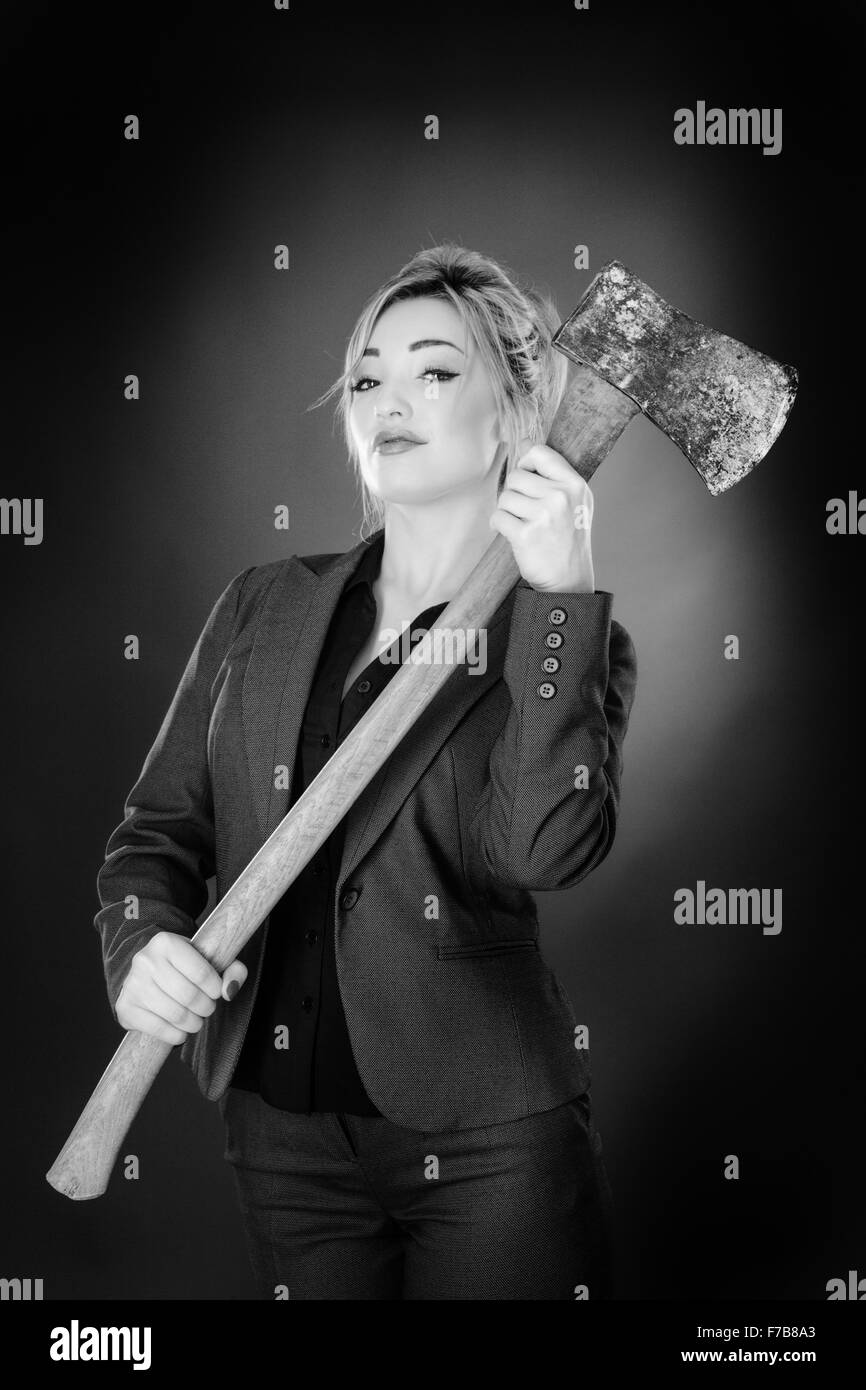 Business donna tenendo un grande ax shot in studio su sfondo grigio Foto Stock
