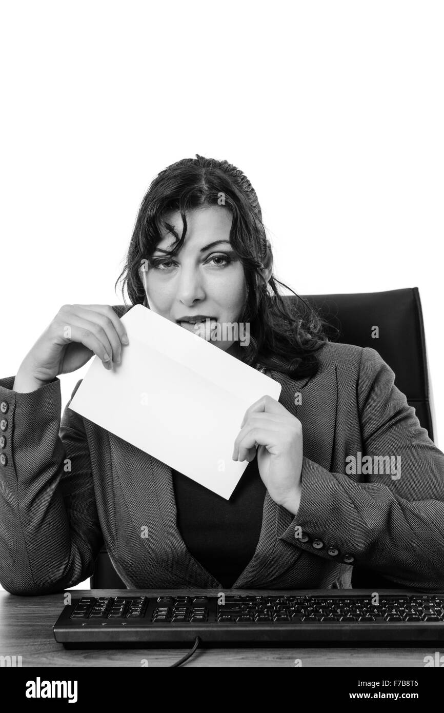 Business donna leccare la busta seduto a sua scrivania Foto Stock