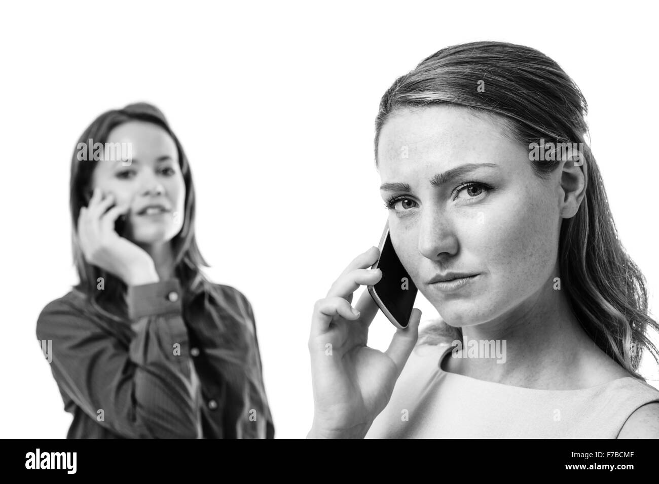 Due donne business uno di fronte all'altra a parlare su un telefono mobile Foto Stock