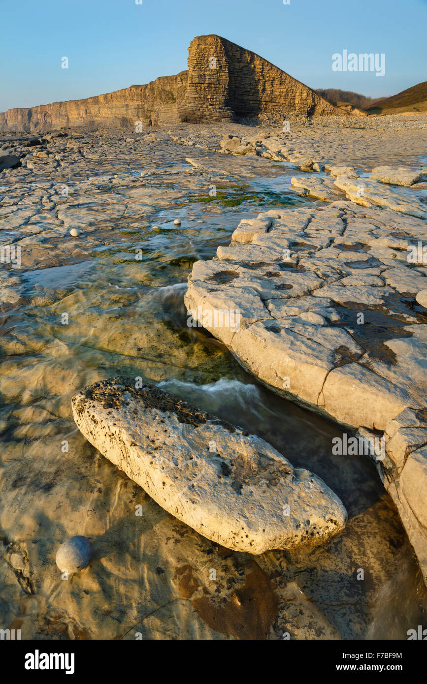 Le splendide formazioni rocciose a bassa marea a Nash punto, Vale of Glamorgan, Galles. Il tramonto è l'illuminazione delle scogliere Foto Stock