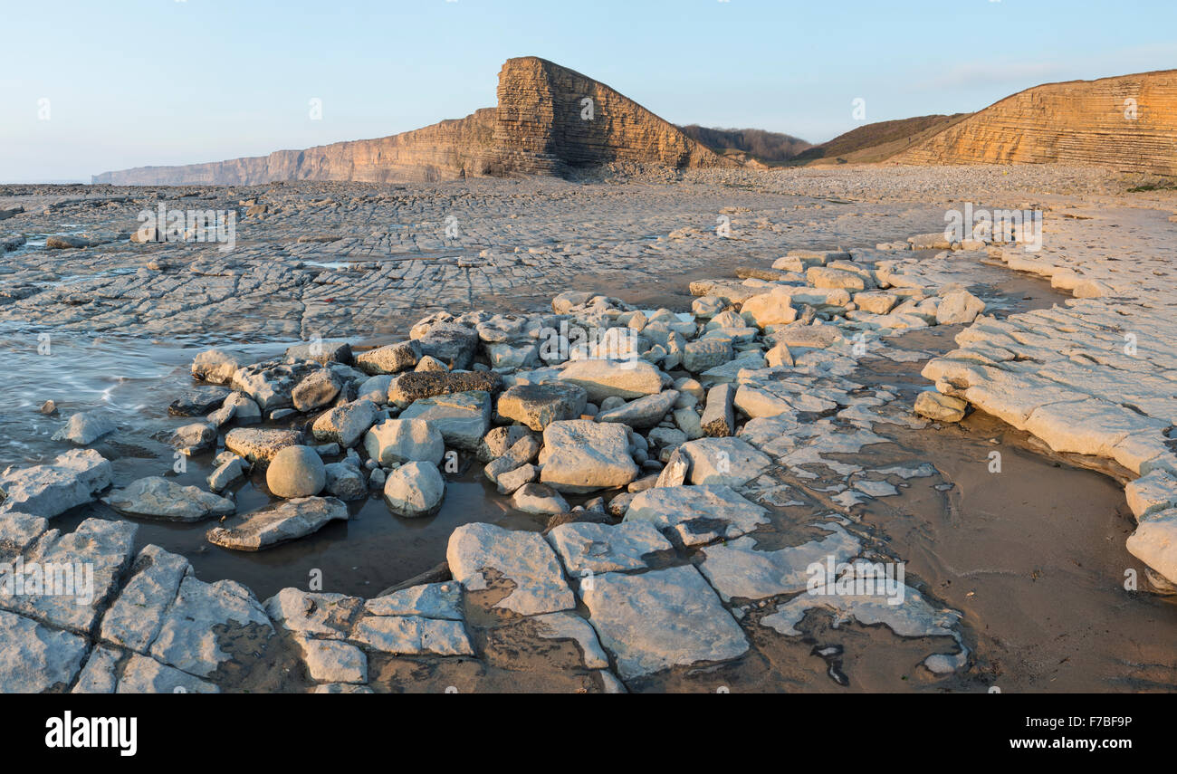 Le splendide formazioni rocciose a bassa marea a Nash punto, Vale of Glamorgan, Galles. Il tramonto è l'illuminazione delle scogliere Foto Stock