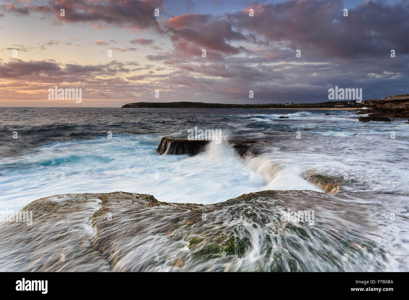 Forti onde surf tirando indietro verso il basso per naturale imbuto roccioso di costa scoscesa dell Oceano Pacifico vicino a Sydney's Maroubra beach a Foto Stock