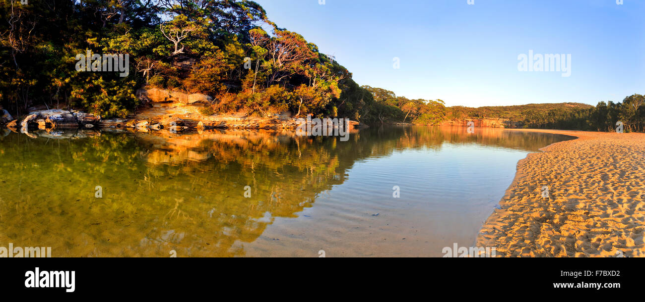 Billabong di acqua dolce in Australia NSW Royal National Park con spiaggia sabbiosa e riflettendo gum alberi di sunrise Foto Stock