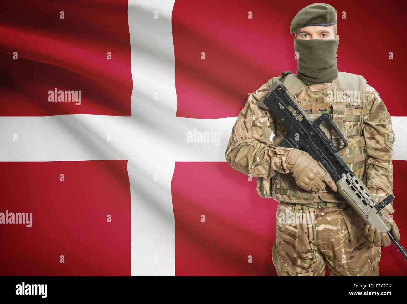 Soldier holding mitragliatrice con bandiera nazionale sullo sfondo - Danimarca Foto Stock