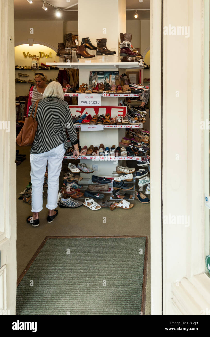 Donne in cerca di scarpe in un negozio di scarpe negozio a Burford , Oxfordshire , Inghilterra , Inghilterra , Regno Unito Foto Stock