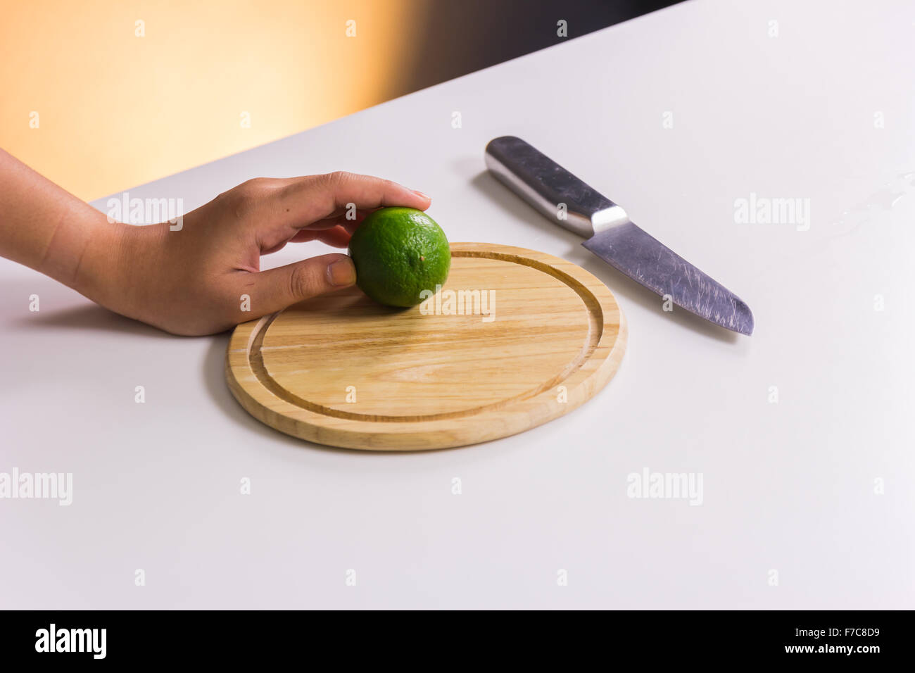 Fresco e acidulo verde lime o limone, tagliata a metà con il coltello sul tagliere Foto Stock