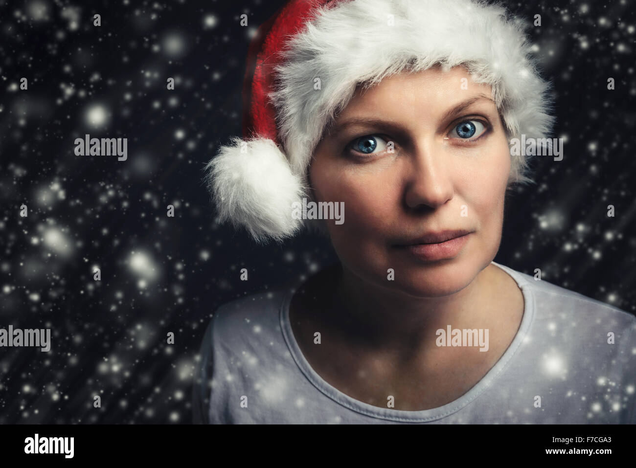 Natale bellezza femminile ritratto con i fiocchi di neve, bella donna adulta con gli occhi blu che indossa Santa Claus hat e guardando a ca Foto Stock