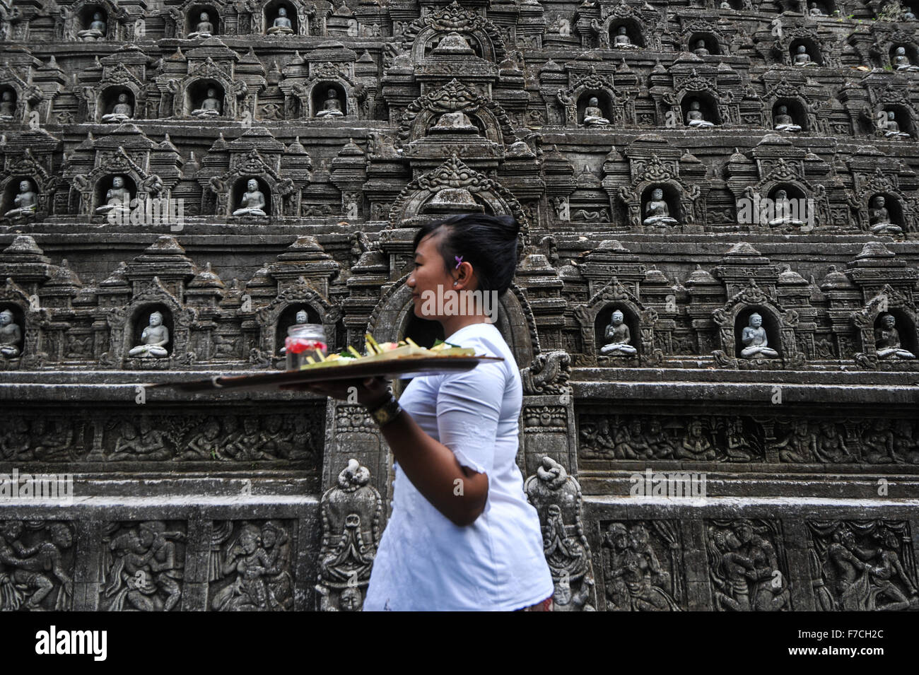 Bali, Indonesia. 29 Nov, 2015. Una donna cammina passato replica del tempio di Borobudur scolpite sulla parete a strapiombo a resort Ayung, Ubud, Bali, Indonesia, nov. 29, 2015. Ubud è una delle zone turistiche di Bali, famoso per la sua cultura e paesaggio naturale. © Veri Sanovri/Xinhua/Alamy Live News Foto Stock