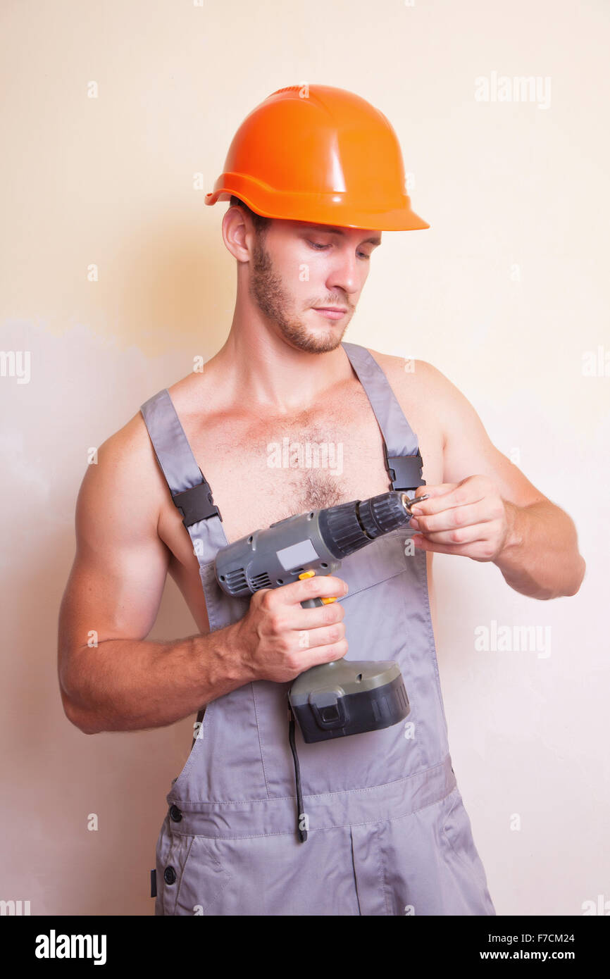 Un uomo in tuta e casco con un cacciavite Foto Stock