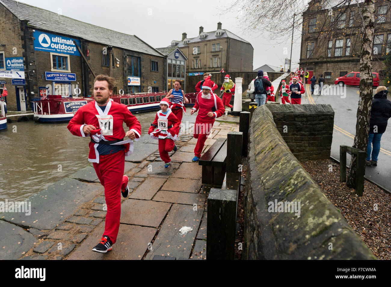 L annuale Santa Fun Run per carità attraverso la Yorkshire città di Skipton. La corsa dura in Aireville Park, il centro città e il Leeds - Liverpool Canal alzaia. Quest'anno i corridori braved heavy rain e venti forti per completare il corso. Foto Stock