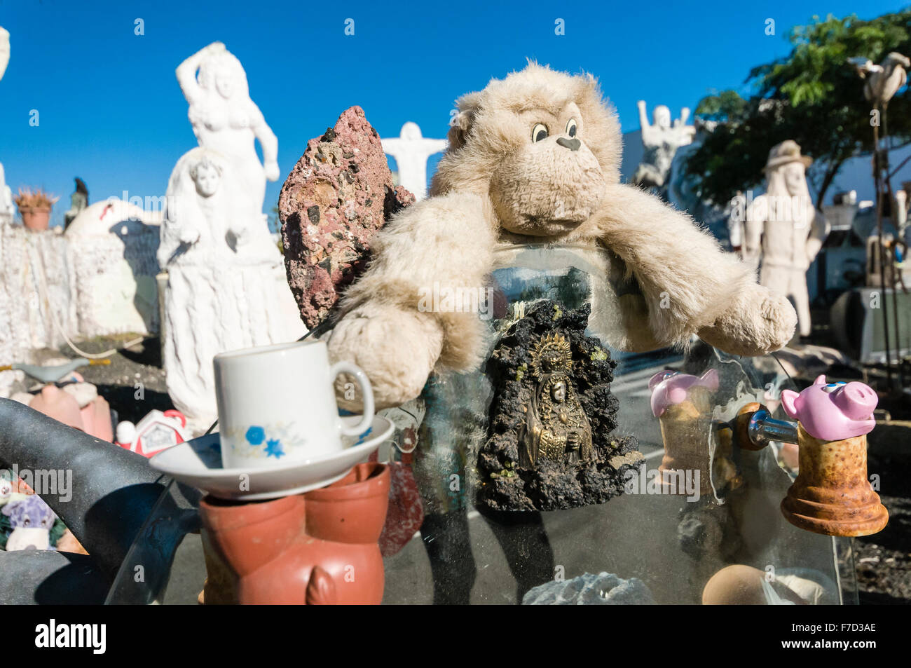 Creepy statue, peluche e oggetti religiosi sul display in un display di arte in un giardino spagnolo. Foto Stock