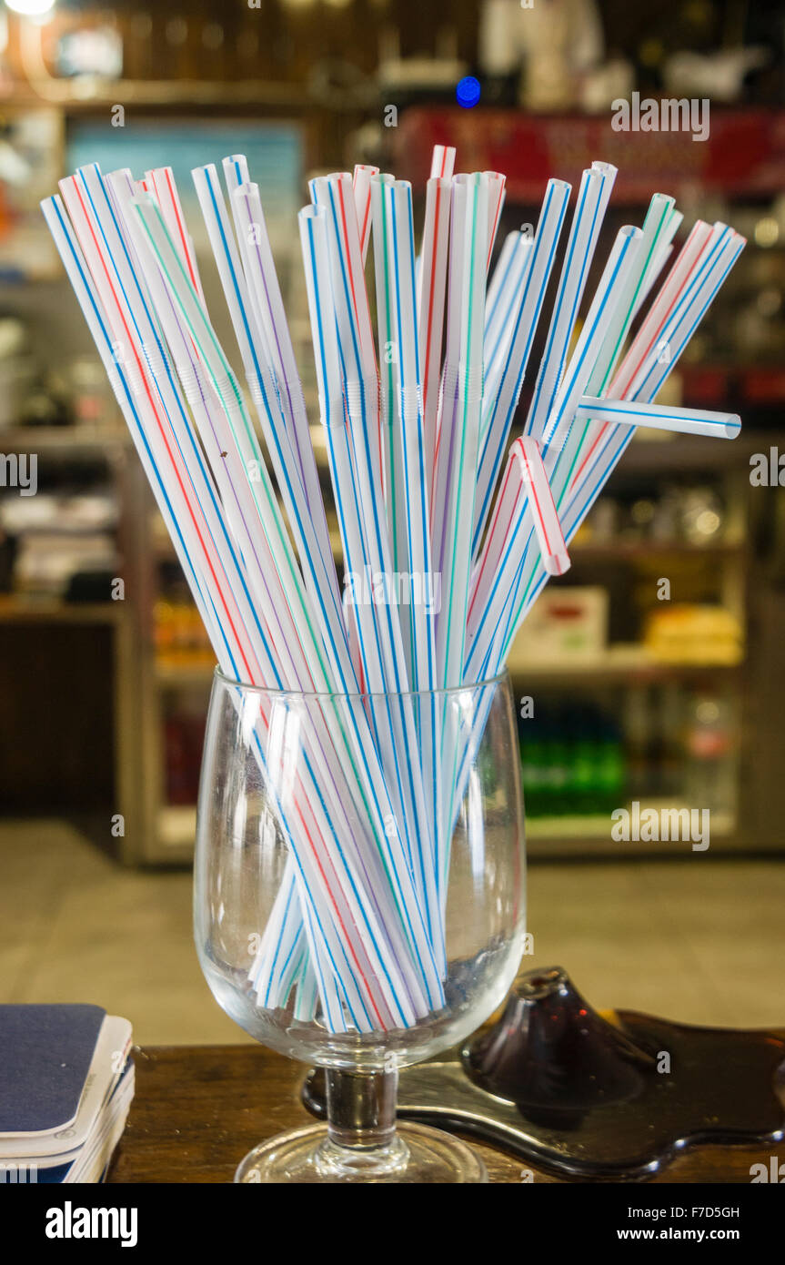 Un vetro con bendy cannucce sul contatore in un bar. Foto Stock