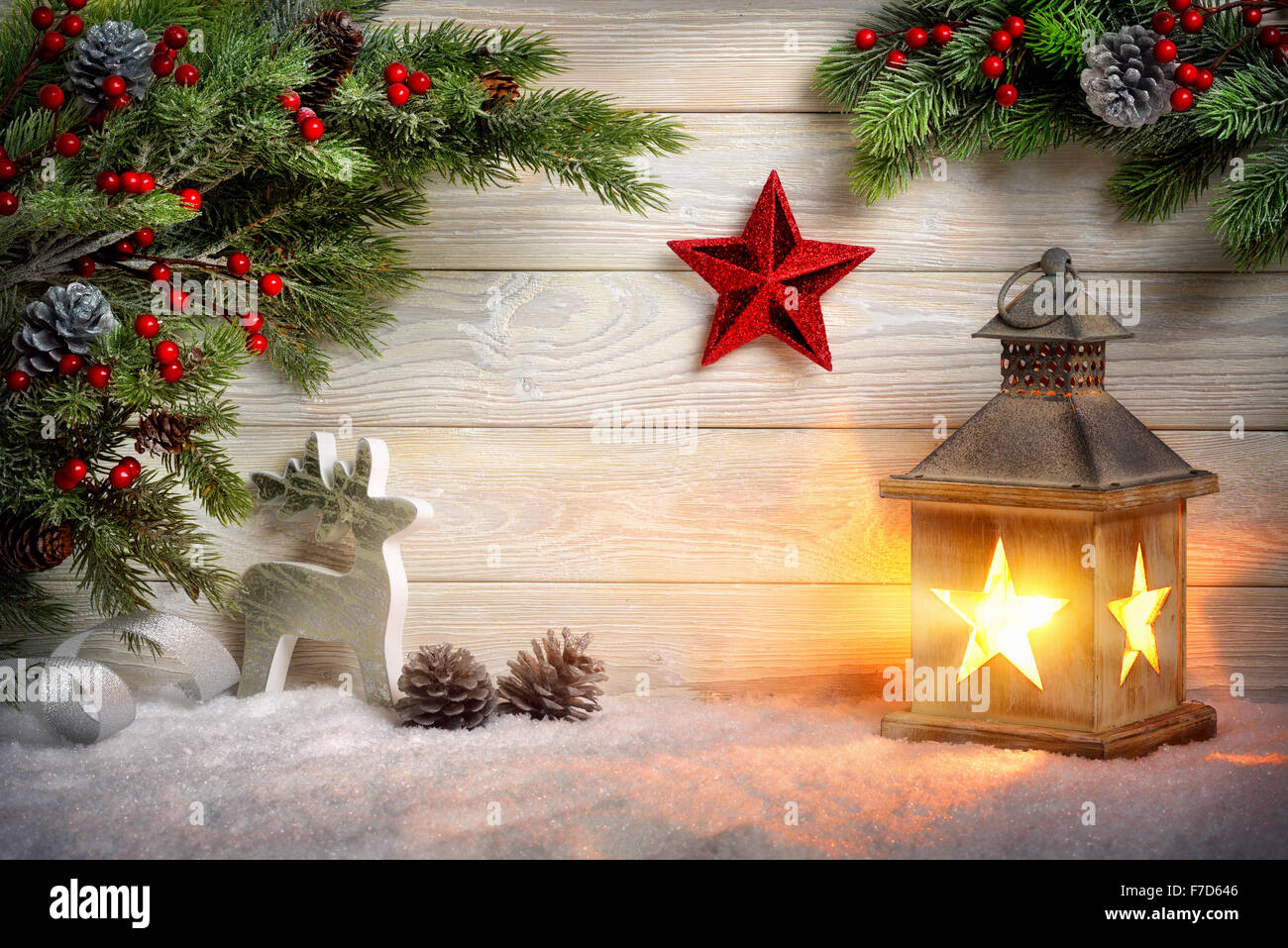 Scena di Natale sfondo con una lanterna, Abete rami, stella rossa, renne e neve nella parte anteriore di una luminosa tavola di legno con ced Foto Stock