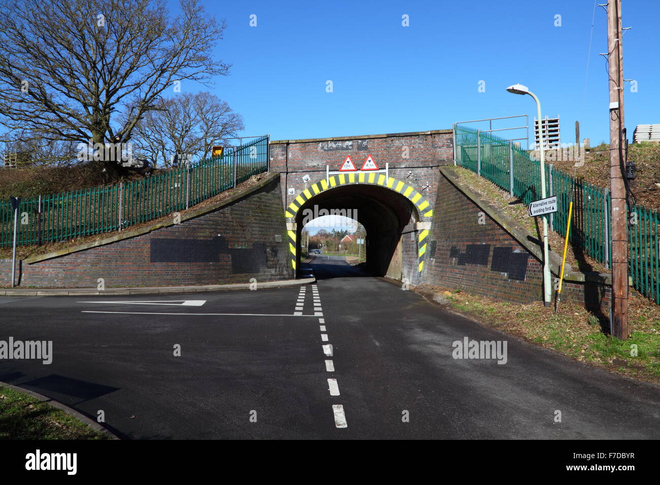 Una rampa su un ponte stradale con un 'T' incrocio che mostra segni di avvertenza per una restrizione di altezza e larghezza dei marcatori di avvertimento sui bordi. Foto Stock