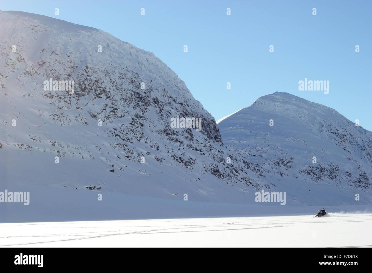 Un snow rider mobile su un lago ghiacciato circondato da montagne, Finndalsvatnet, Norvegia Foto Stock
