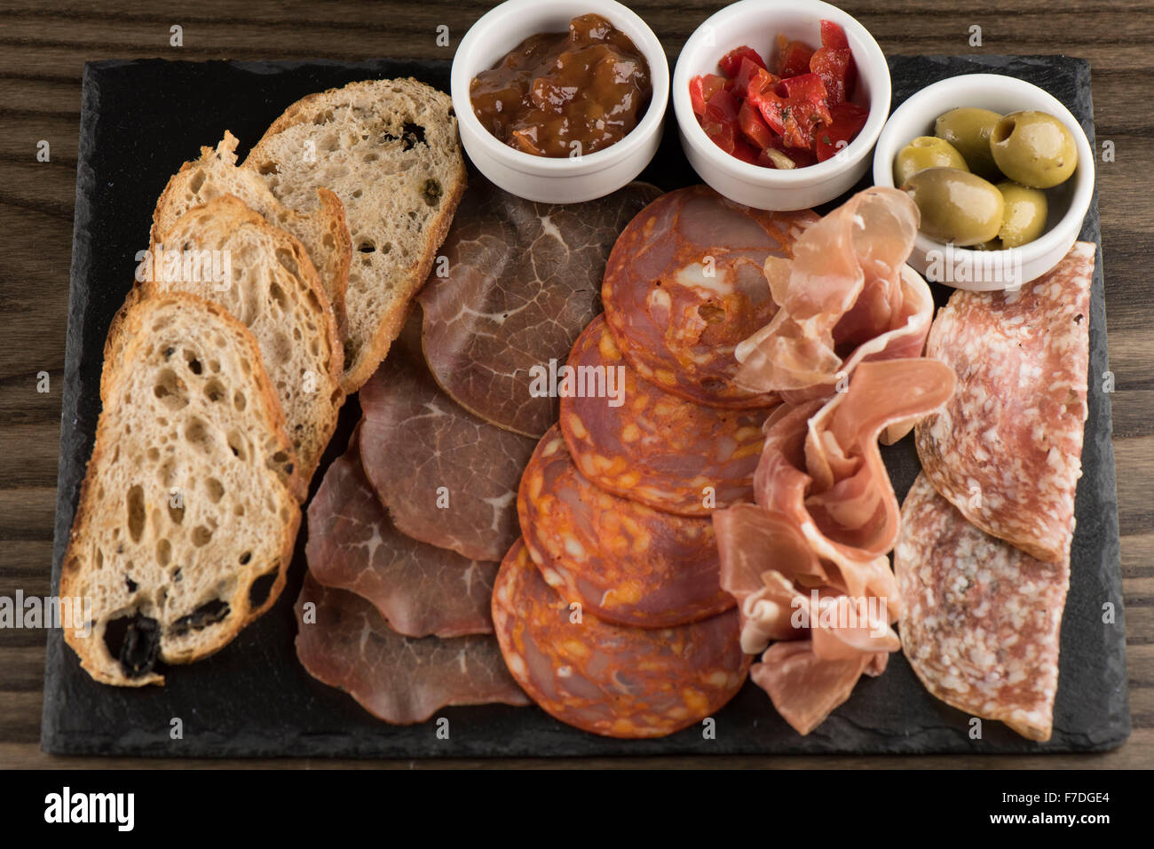 Italian salumi con chutney, olive e peperoncino servito come antipasto in un ristorante italiano. Foto Stock