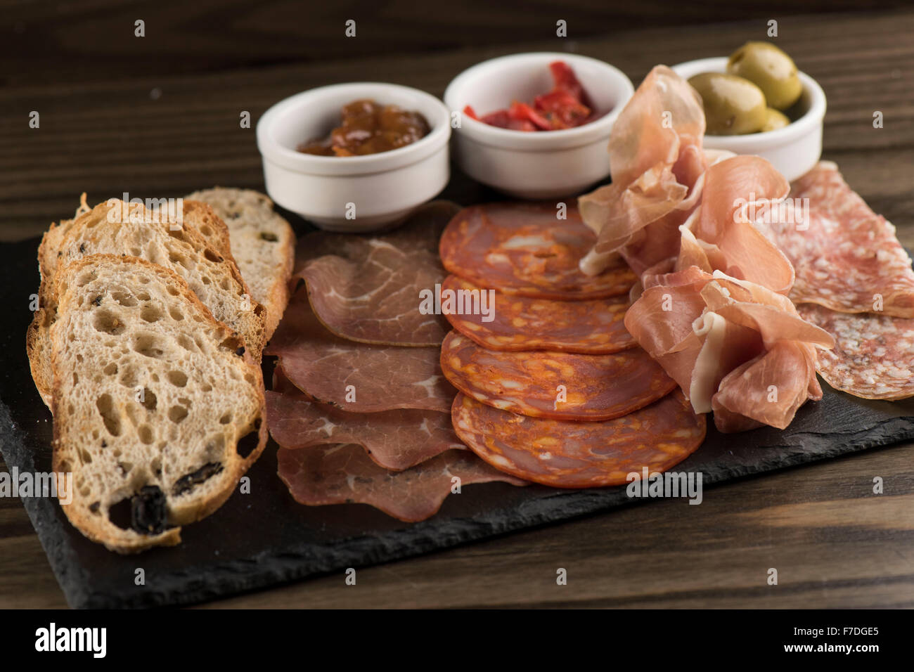 Italian salumi con chutney, olive e peperoncino servito come antipasto in un ristorante italiano. Foto Stock