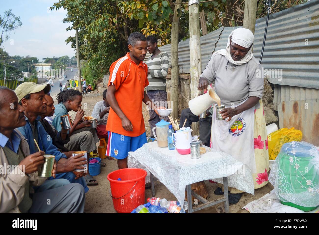 Una donna etiope distributore vende un Etiope tradizionale bevanda fermentata chiamato shameta dalla strada al giorno gli operai in Etiopia ad Addis Abeba. La donna è stata in grado di impostare il cavalletto con l aiuto di USAID assistenza. Foto Stock
