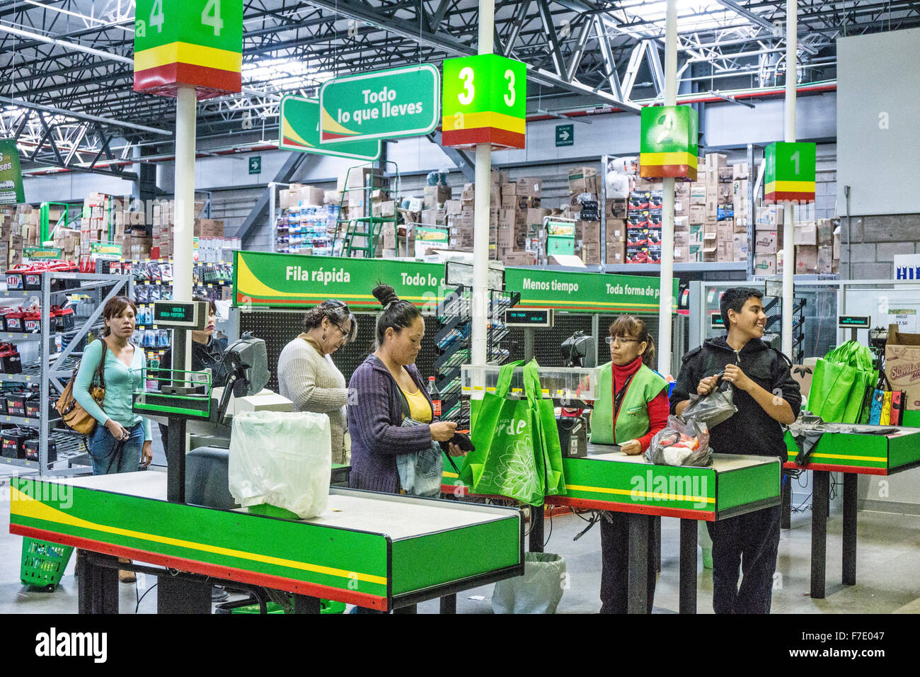 Energico giovane uomo borse degli acquisti come annoiato ai clienti di passare attraverso il checkout express linea nella scatola grande catena negozio Bodega Aurrera Foto Stock