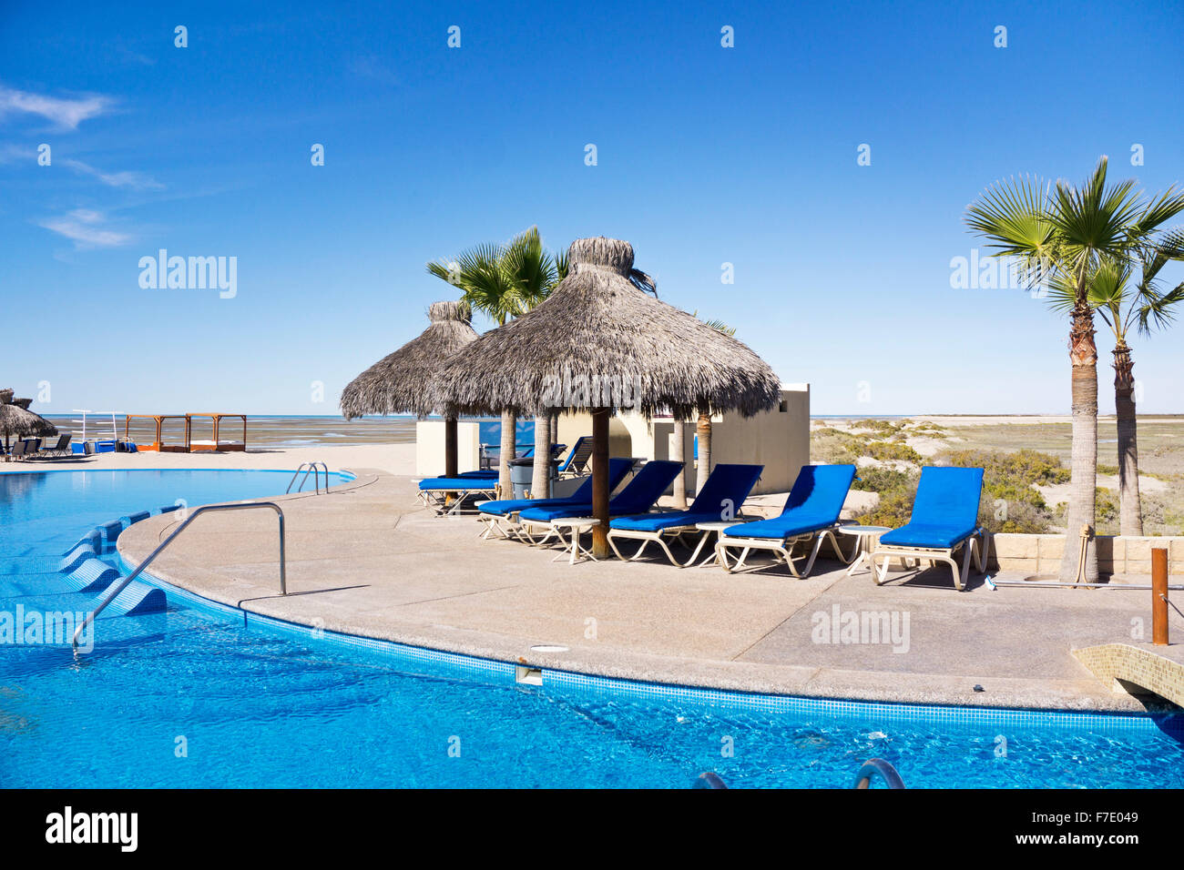 Numerose palapas forniscono ombra per sedie a sdraio raggruppati intorno bella piscina curvilineo affacciato sulla spiaggia di Laguna Shores Foto Stock