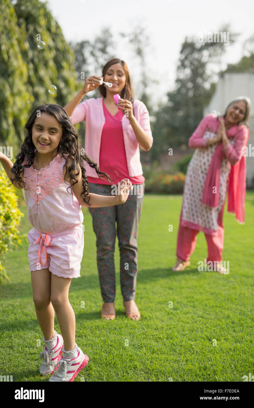 Tre generazioni di femmine in giardino con la madre a soffiare bolle e figlia (4-5) Foto Stock