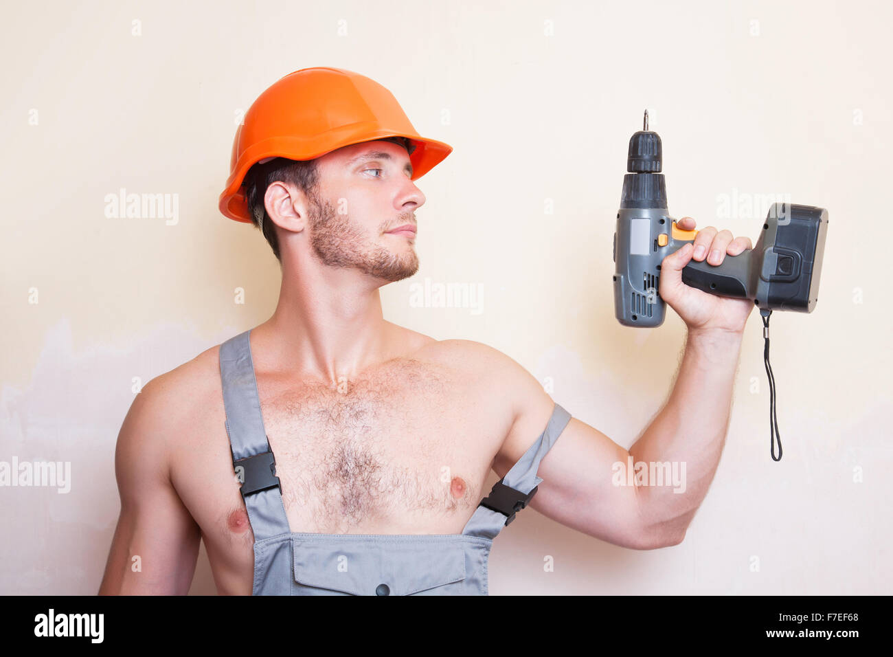 Un uomo in tuta e casco con un cacciavite Foto Stock