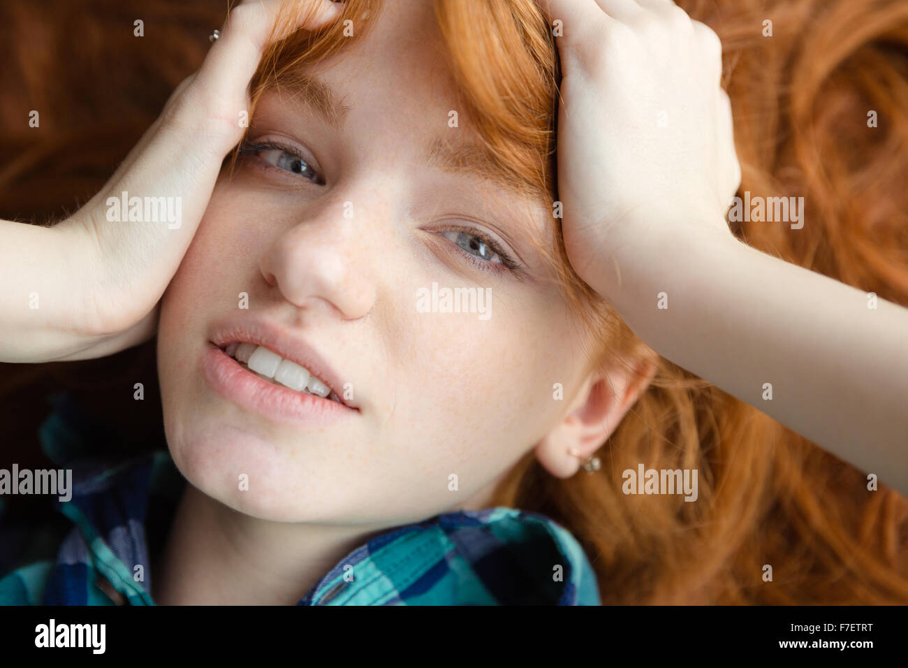 Primo piano della bella carino redhead ragazza in blu camicia a scacchi sdraiato sul pavimento con capelli tousled Foto Stock