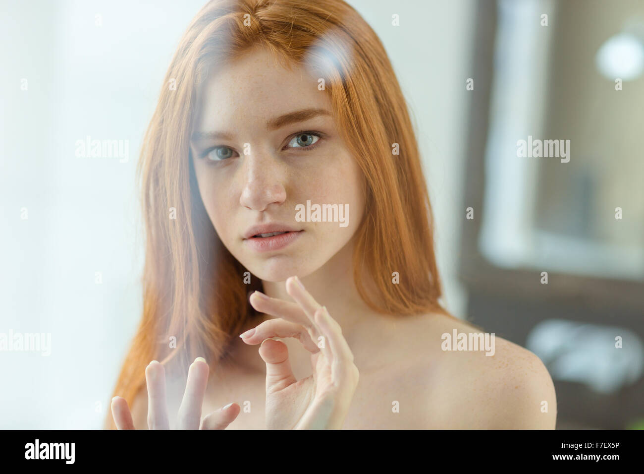 Ritratto di un redhead donna che guarda la telecamera attraverso la finestra Foto Stock