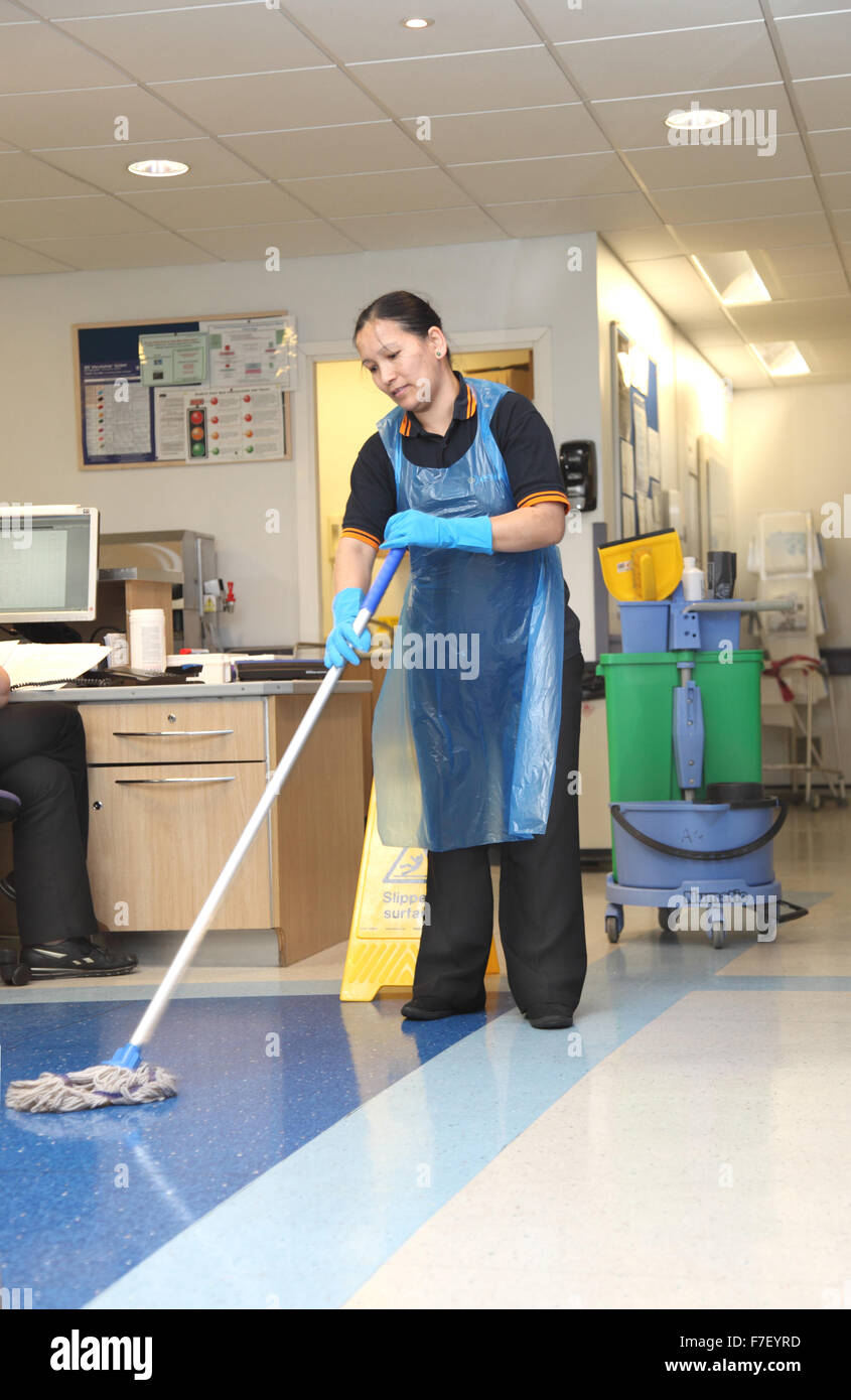 Un ospedale cleaner mops il pavimento in un reparto in un moderno ospedale del Regno Unito Foto Stock
