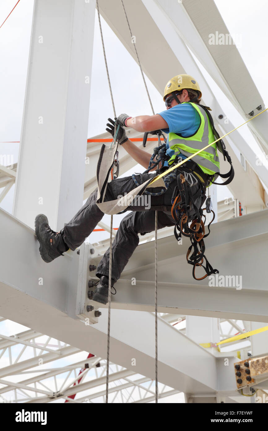 Un lavoratore edile utilizza corde per accedere al tetto in acciaio per la costruzione di un nuovo edificio a Londra. Foto Stock