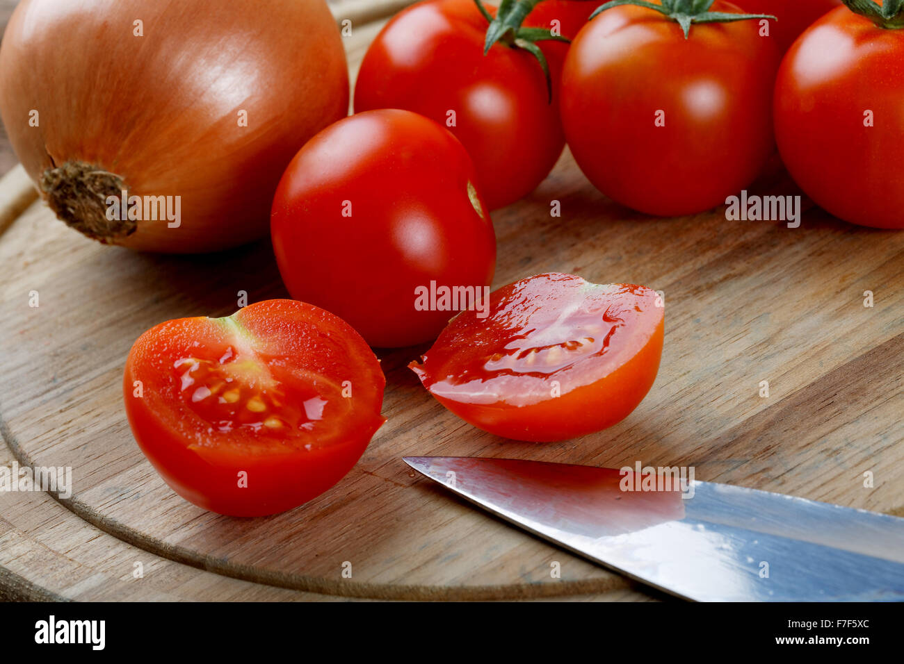 Cipolle pomodori e un coltello su un tagliere Foto Stock
