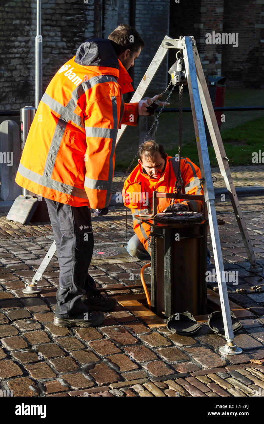 Dordrecht, Paesi Bassi - 23 Novembre 2015: lavoratori tecnico Riparazione di colonnine automatiche impostate in una mattonella strada asfaltata Foto Stock