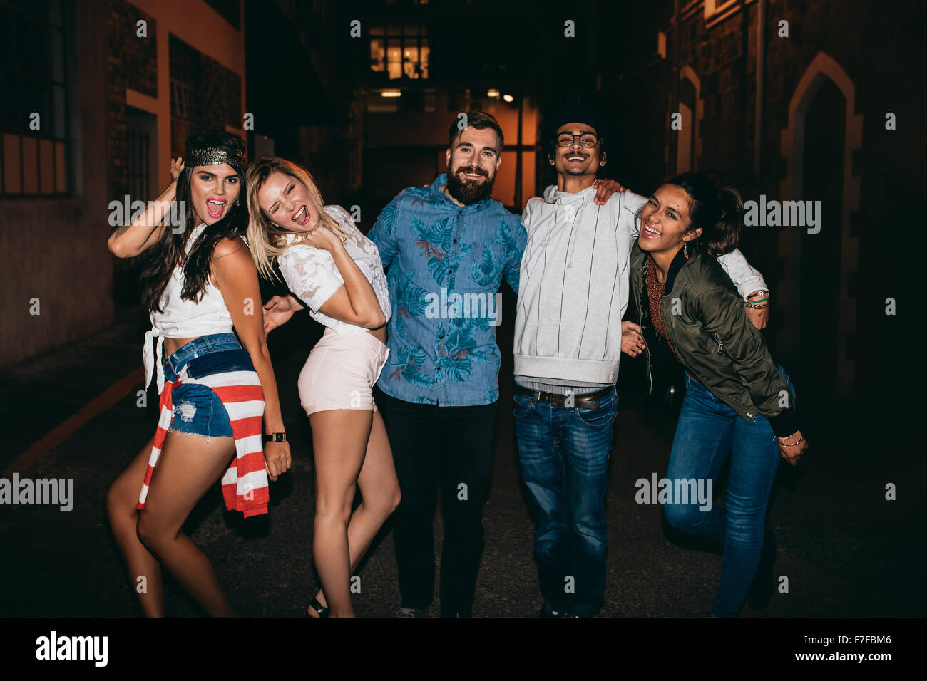 Ritratto di giovani uomini e donne che cercano in telecamera a ridere. Multirazziale del gruppo di giovani amici appendere fuori all'aperto in parte. Foto Stock