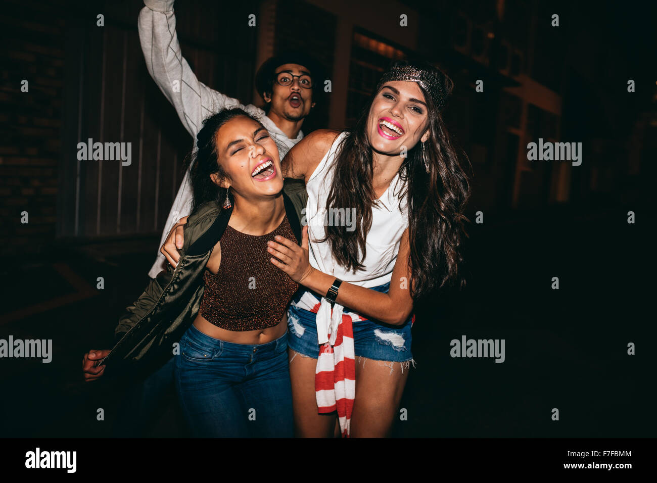 Ritratto di tre giovani amici avente parte all'aperto. Allegro giovani migliori amici appendere fuori a notte. Foto Stock