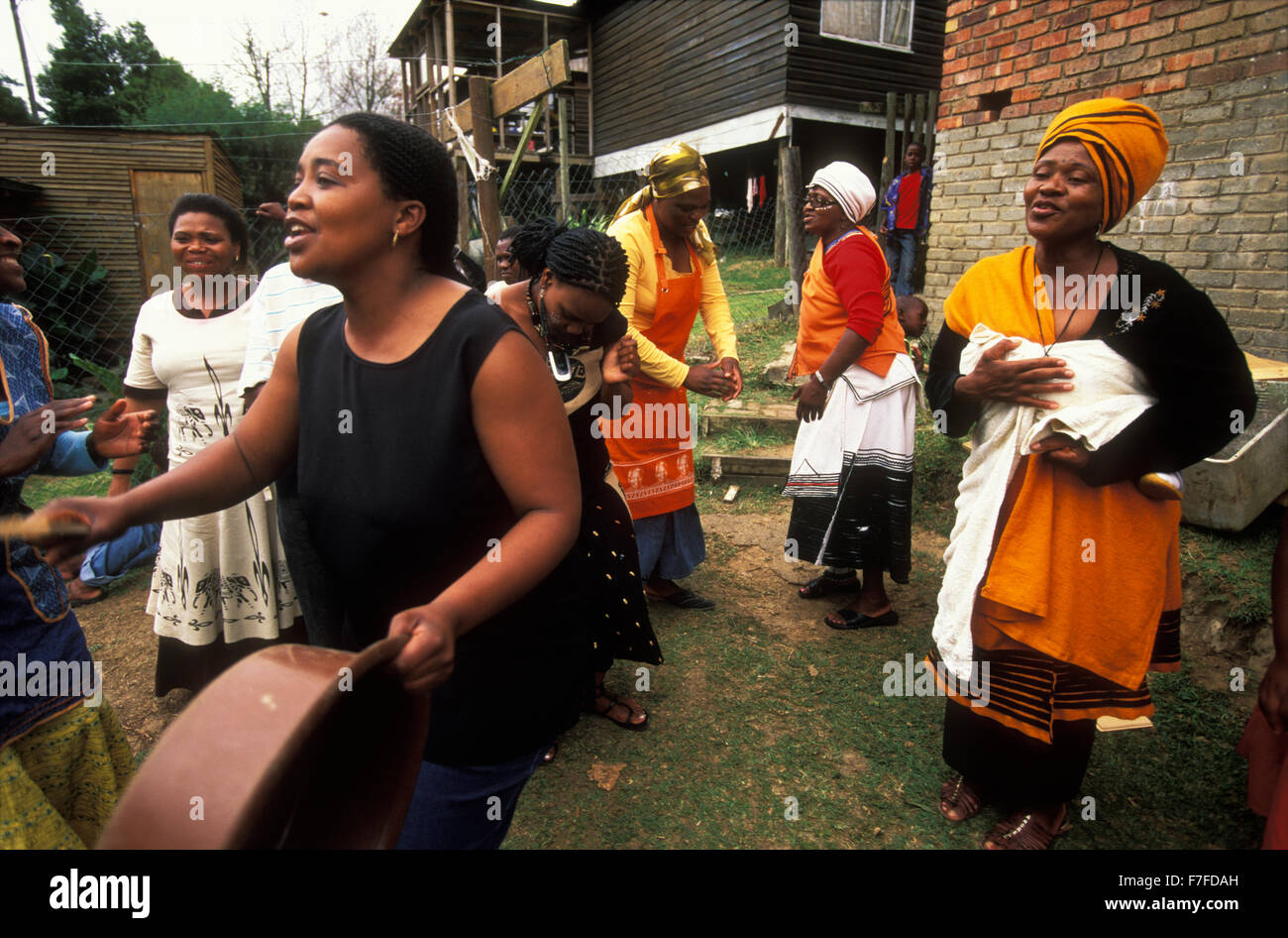 Xhosa donne cantare e ballare mentre casa accogliente giovani membri maschi della famiglia, che hanno trascorso un mese in un accampamento di iniziazione Foto Stock