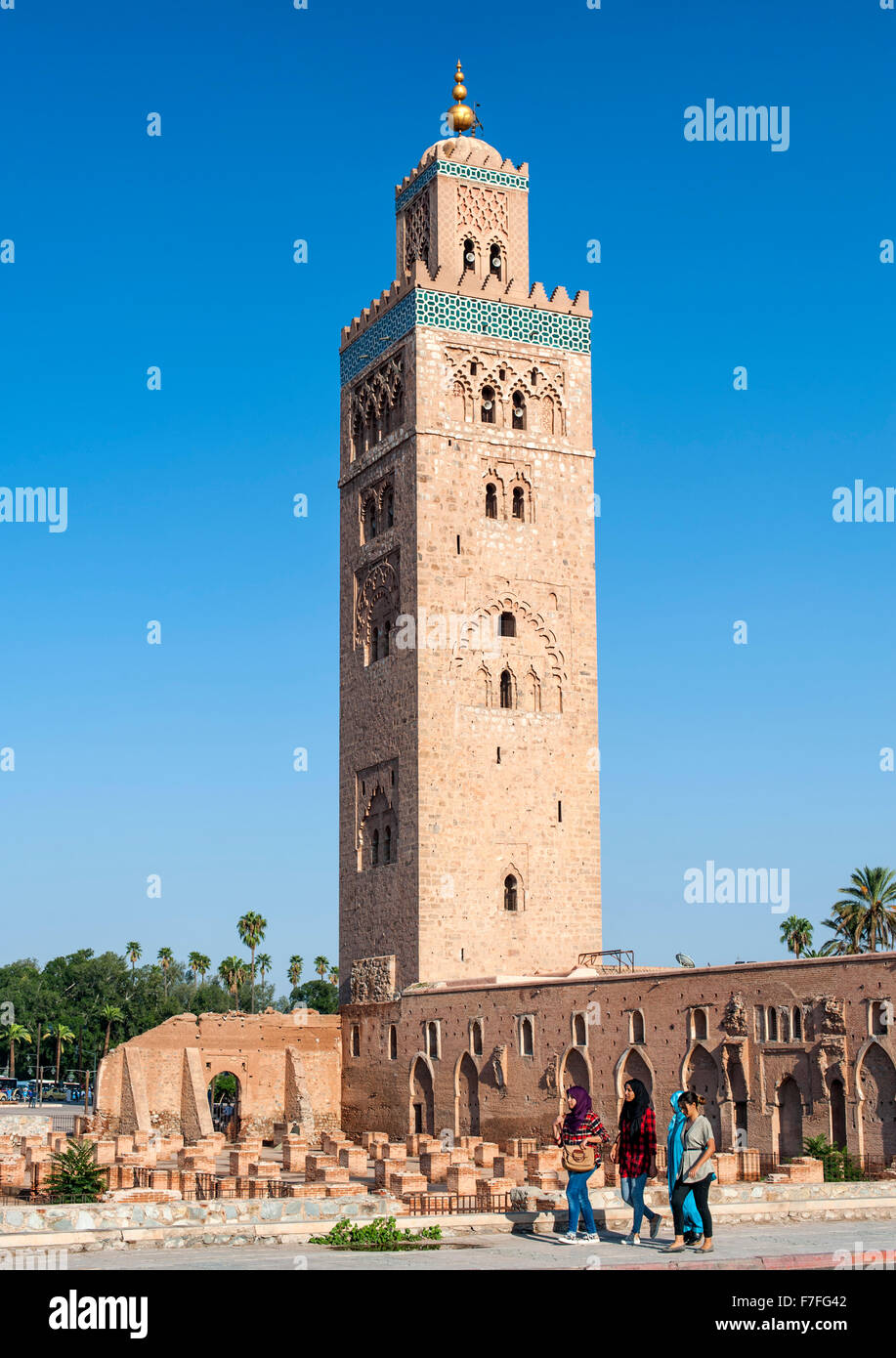 Quattro donne oltrepassando la moschea di Koutoubia di Marrakech, Marocco. Foto Stock