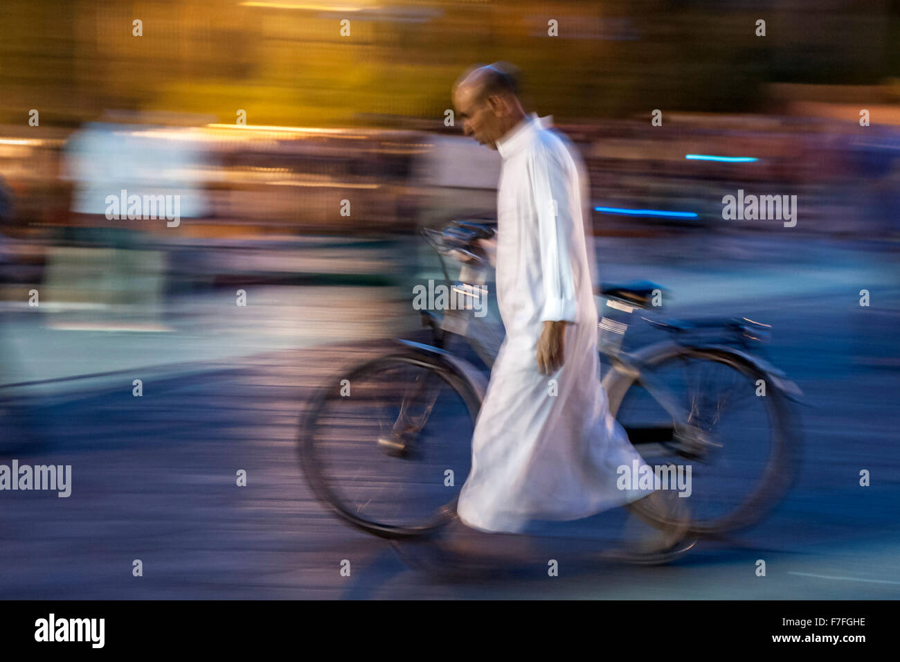 Uomo marocchino a piedi con la sua bicicletta in Piazza Jemaa El Fna a Marrakech, Marocco. Foto Stock