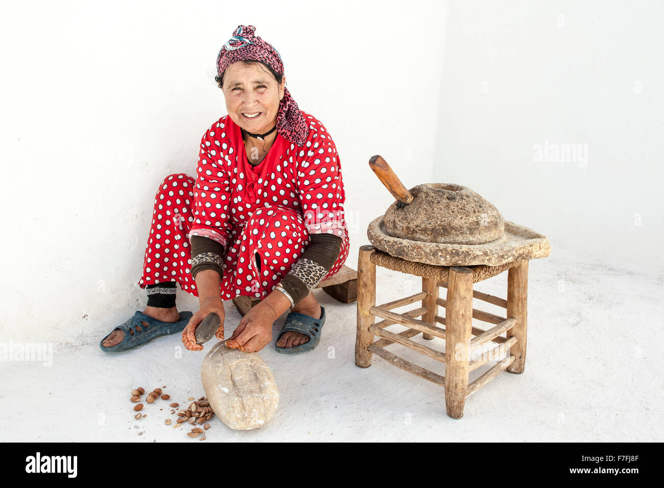 Donna marocchina di cracking dadi argan a premerli per olio. Foto Stock