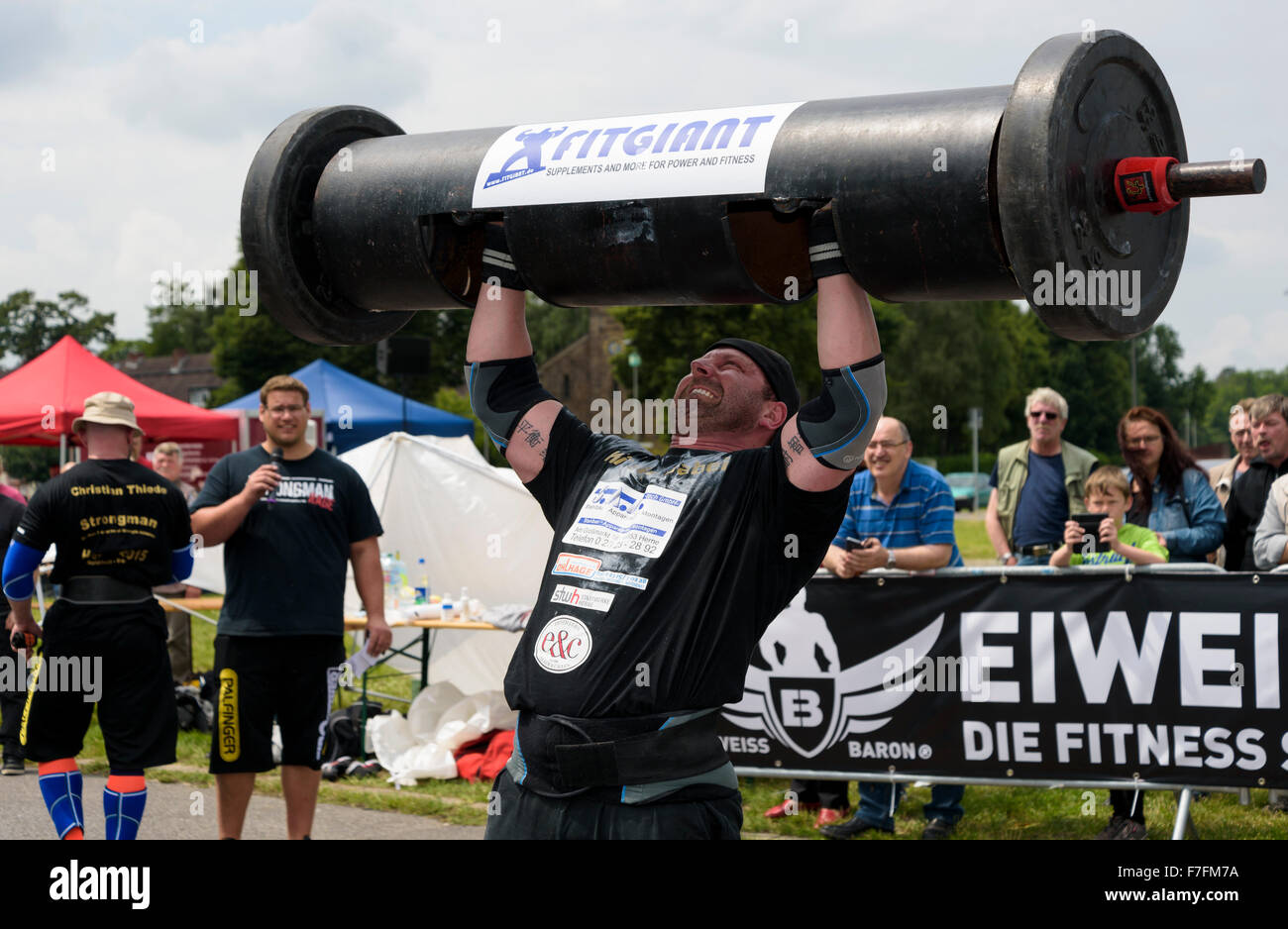 Un uomo forte dimostra la sua forza ad un pubblico di atletica leggera evento sportivo. Foto Stock