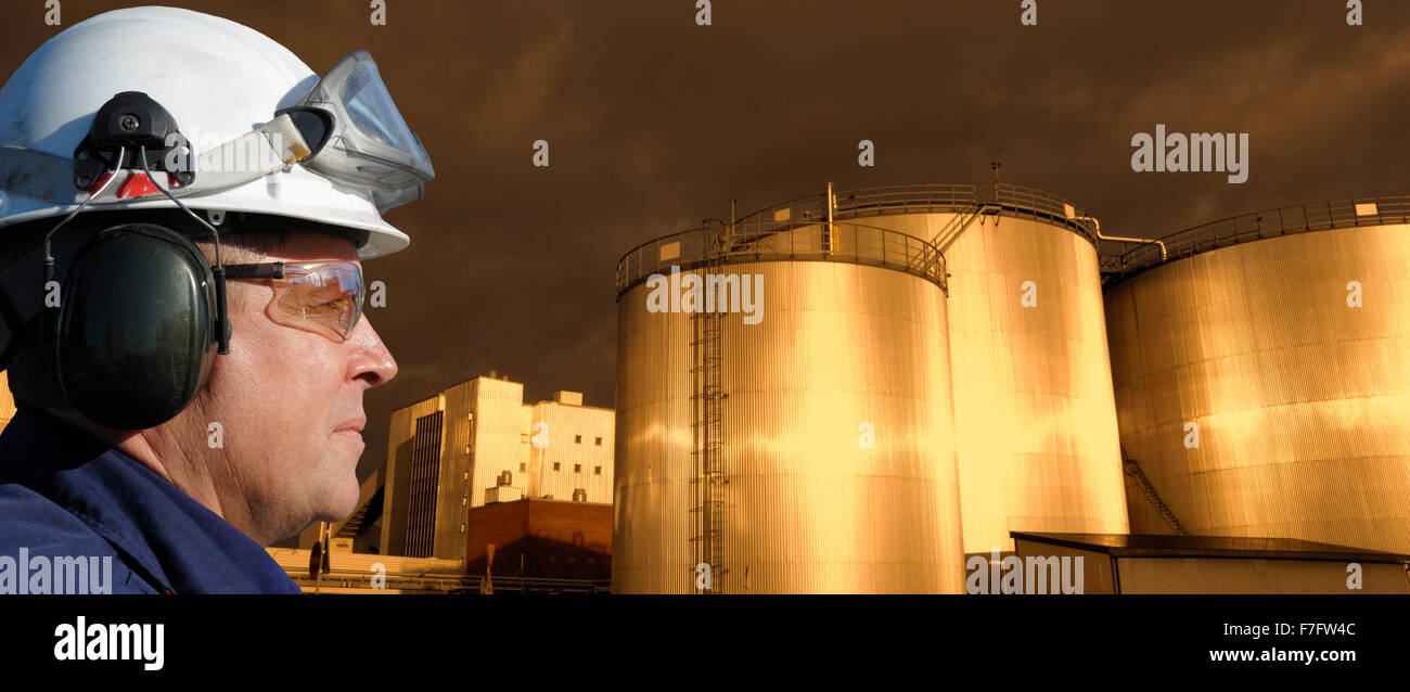 Il petrolio e il gas lavoratore con combustibile grande-serbatoi, serbatoi di raffineria in background Foto Stock