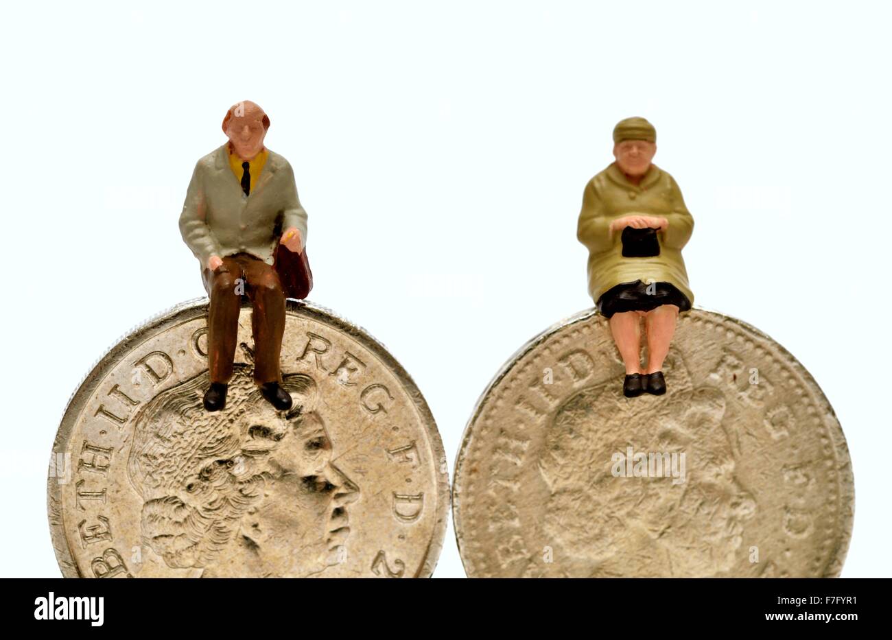 Miniatura gente seduta su una libbra di monete Foto Stock